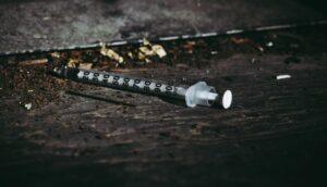 Close-up of a discarded syringe on a rough surface highlighting addiction issues.
